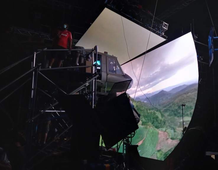A helicopter set in a virtual production studio, surrounded by a curved LED screen.