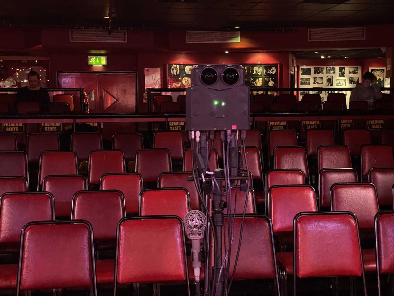The Meta 2 3D camera on a stand in the front row of the Comedy Store, facing the stage over red seats.