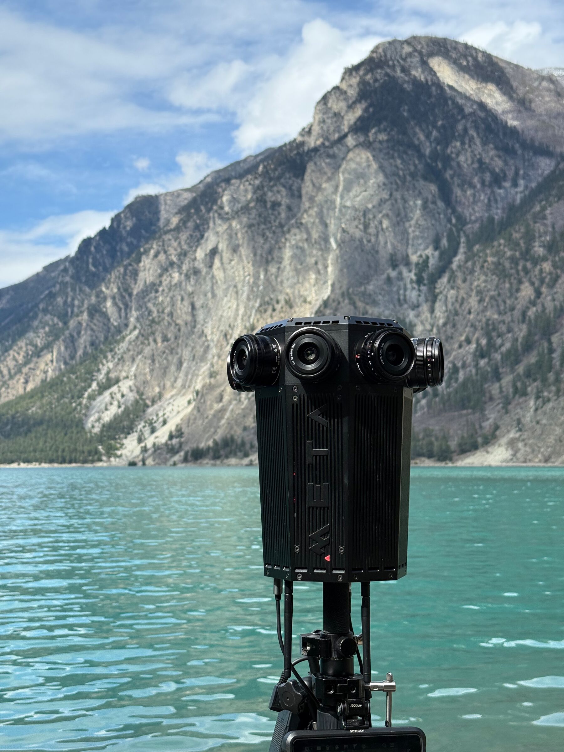 The Meta Four on a tripod at the edge of a turquoise mountain lake, with a granite peak behind.